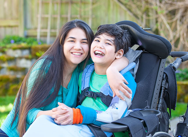 caregiver smiling with boy in wheelchair